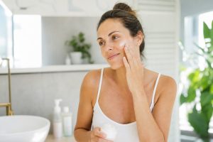 Frau pflegt ihre Haut morgens mit leichter Sommerpflege und Sonnenschutz.
